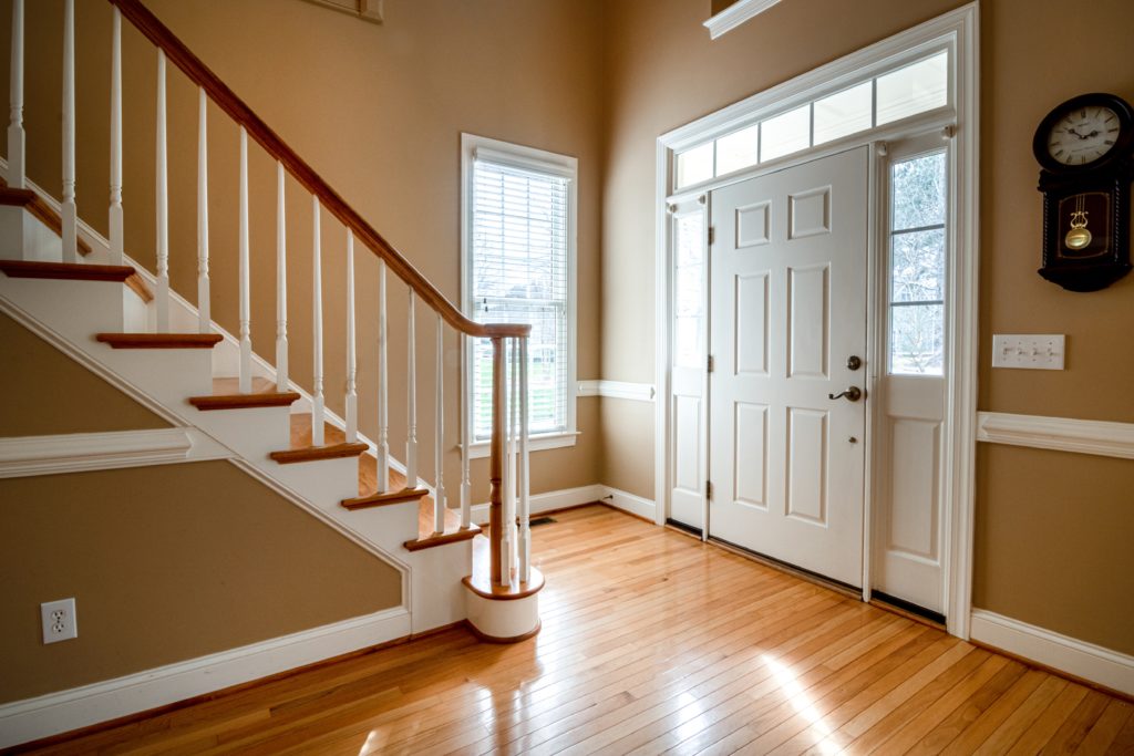 Interior shot of home with a wooden staircase leading to an energy efficient, white entry door.