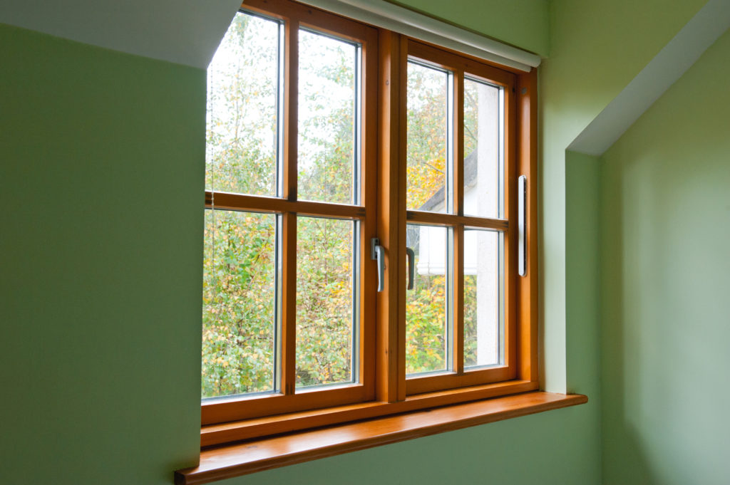 Tilt turn wooden window frame in a home in autumn.